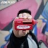 Hand holding a red FOR PLUS 50000 Puffs 50k disposable vape kit in front of a colorful graffiti wall background.